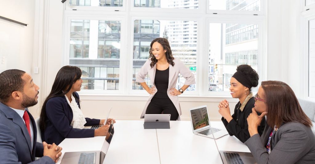 Diverse team engaged in a business meeting with laptops in a modern office setting.